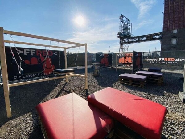Rope bondage Spielbereich mit Kissen und Banner auf einer Outdoor-Dachterrasse.