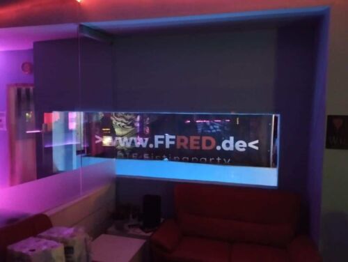 Fistwerk: Fisting Community und XXL-Toys in dunklem Raum mit buntem Licht.