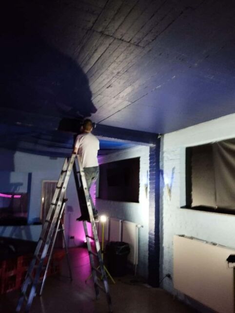 Lackierer bei der Renovierung einer Bar mit dunklem Deckenhimmel.