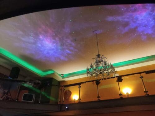 Himmel mit Sternenprojektor und Kronleuchter, farbige Lichtprojektion an der Decke.
