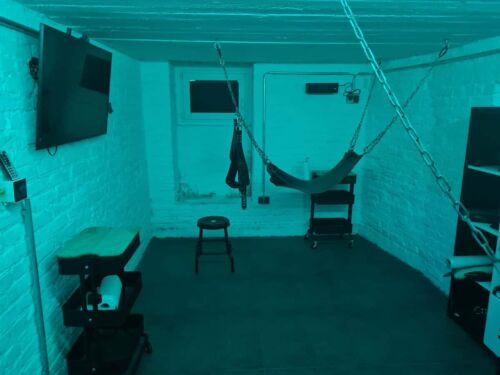 Stille BDSM-Dungeon mit H&auml;ngematte und Chains, dunkle Atmosph&auml;re, private Fetisch-Raum.