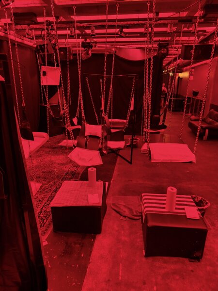 H&auml;ngende Schaukeln und Sitzgelegenheiten im Fistwerk, beleuchtet mit rotem Licht, in einem stilvollen, modernen Raum in Stuttgart.