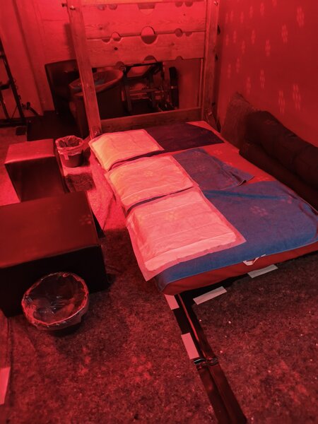 Intimer Raum bei Fistwerk in Stuttgart mit rotem Licht, Bett, Kissen und Sitzgelegenheit, ideal f&uuml;r private Momente.